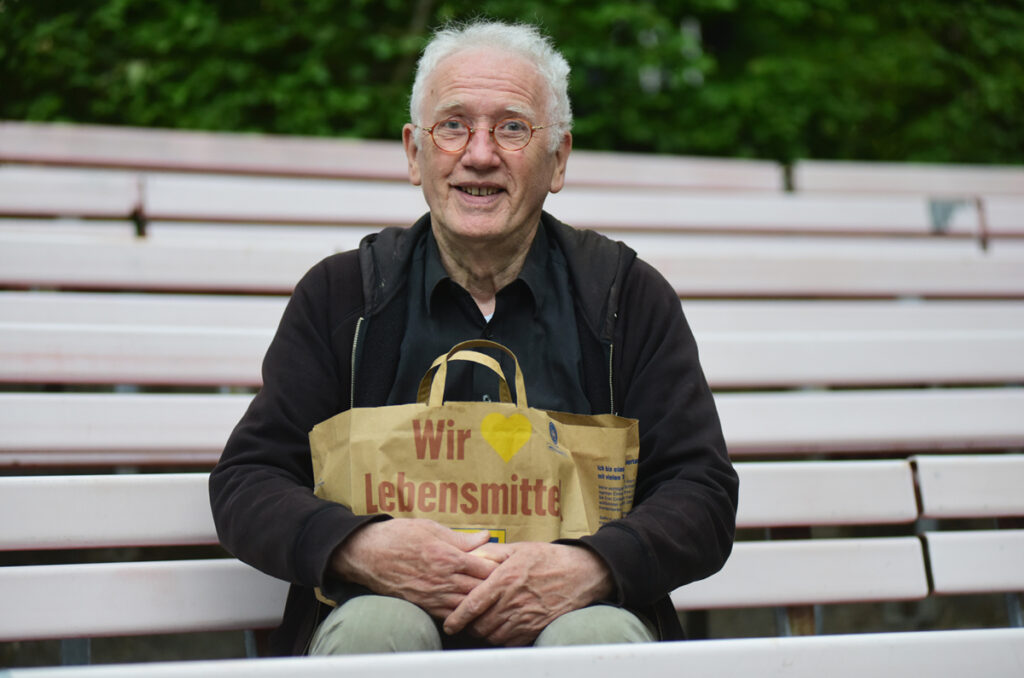 Der Filmemacher Albrecht Metzger vor der Premiere seines Films Ton Steine Scherben: Tour 83,  mit einer Edekatüte, grinst in die Kamera, Foto: Sönke Tollkühn